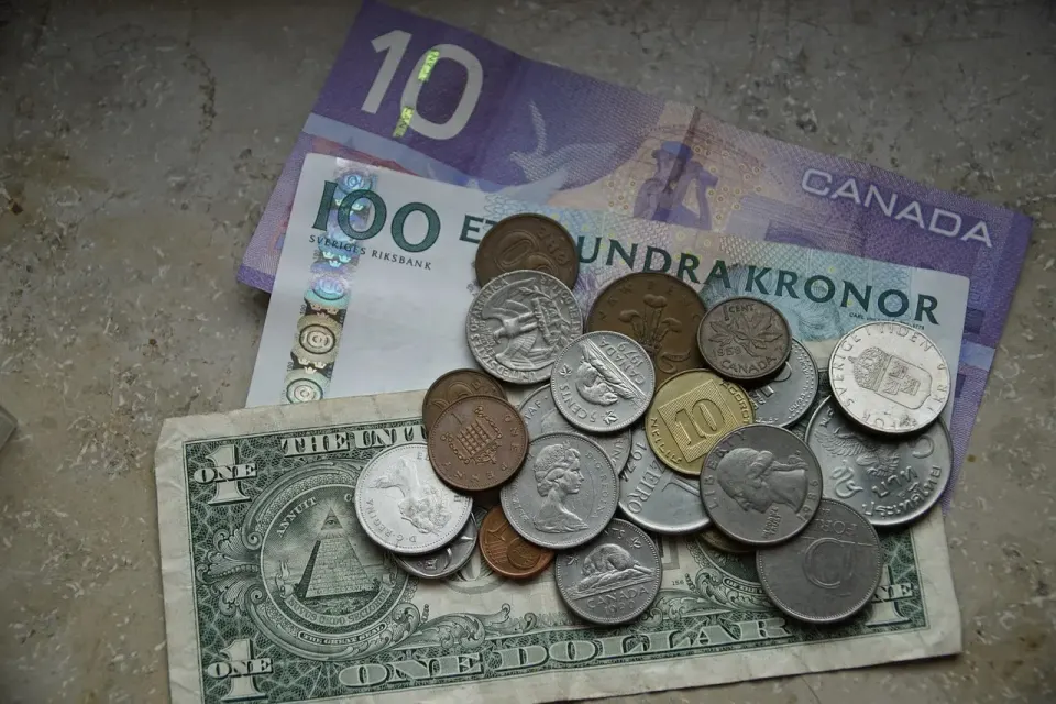 Coins and banknotes in several currencies on top of a world map