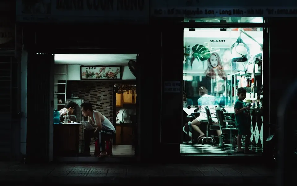 Lit shopfronts on a Hanoi street at night