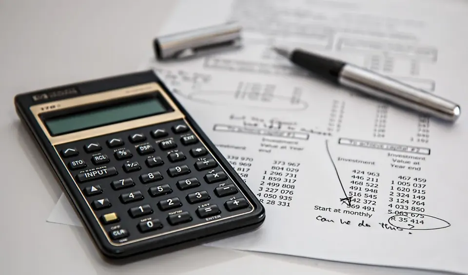 A calculator and printed figures on a desk, used for checking supplier records and invoices