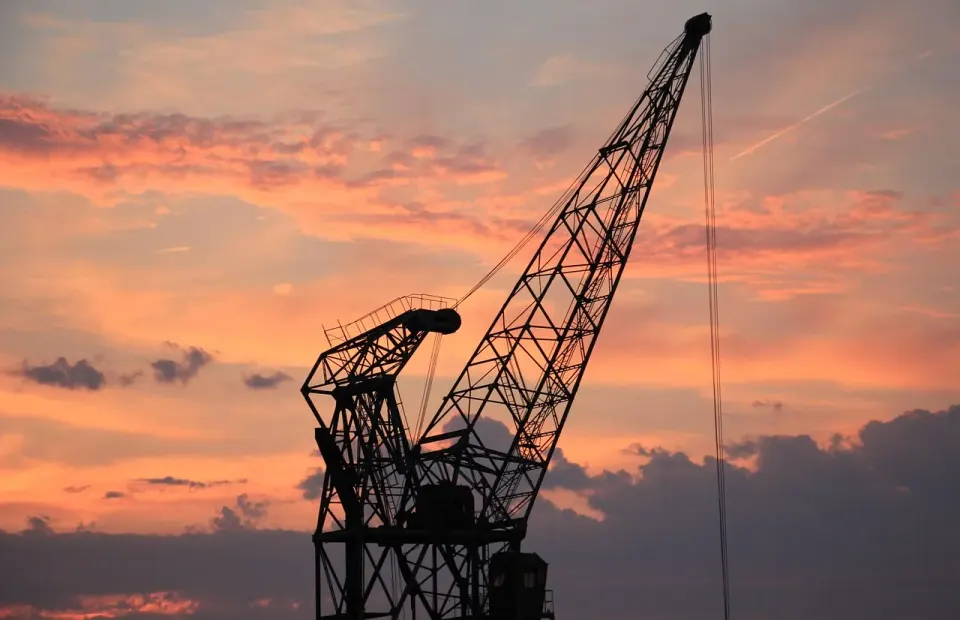 A harbor crane silhouetted against the evening sky at a port