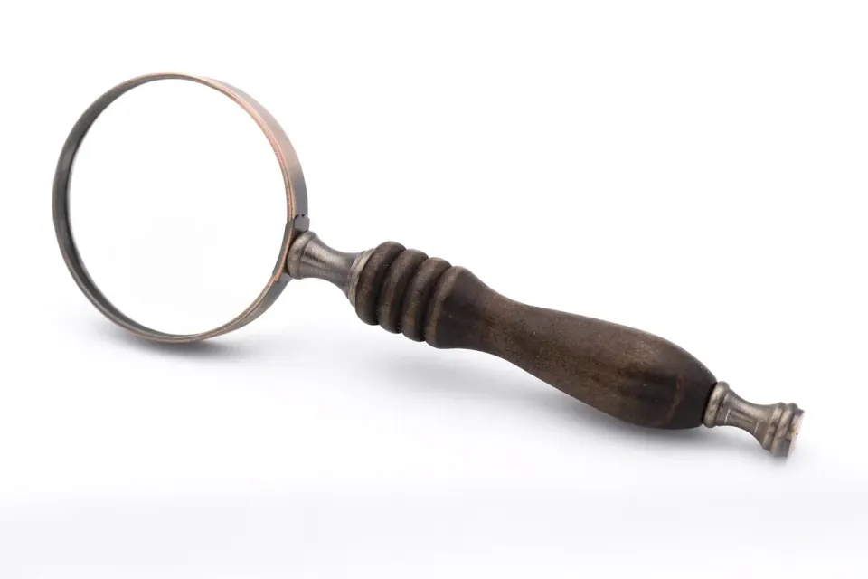 A magnifying glass resting on a printed page, ready for close reading